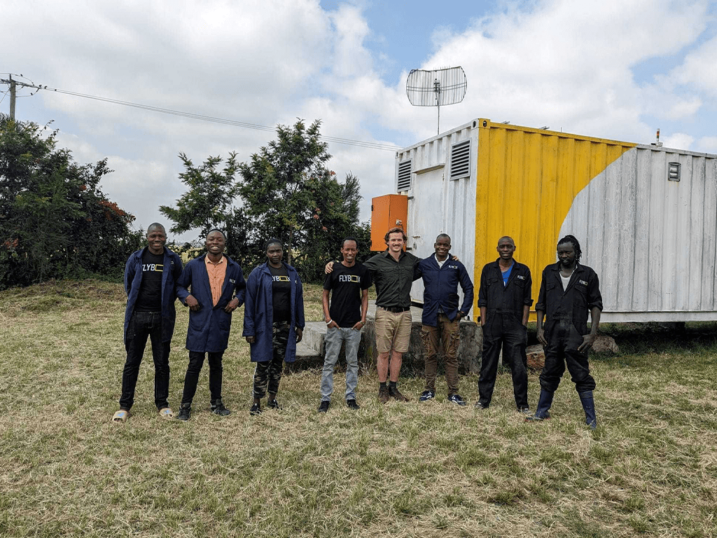 Flybox® team standing in front of a yellow and white insect farming container in Kenya