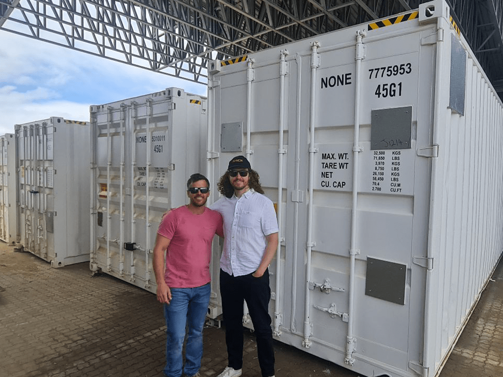Flybox® team standing in front of large white insect farming containers