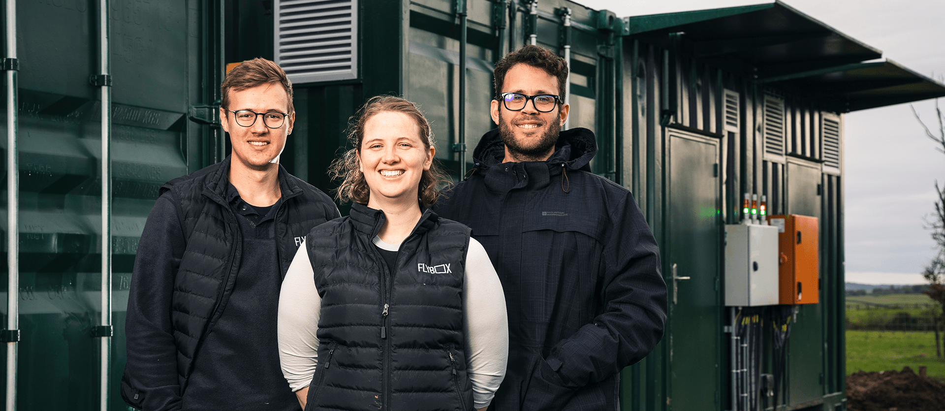 Flybox staff standing in front of large green insect farming containers